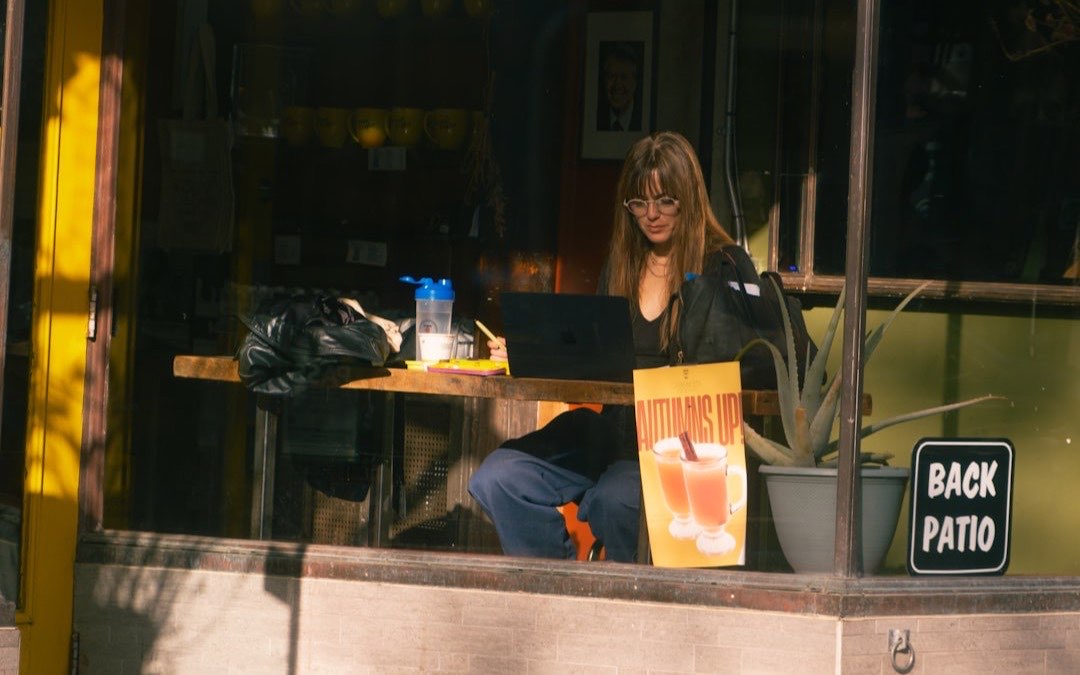 Woman working on a laptop at an outdoor cafe table