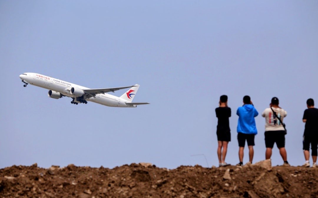 Travellers watching a plane take off from the airport terminal