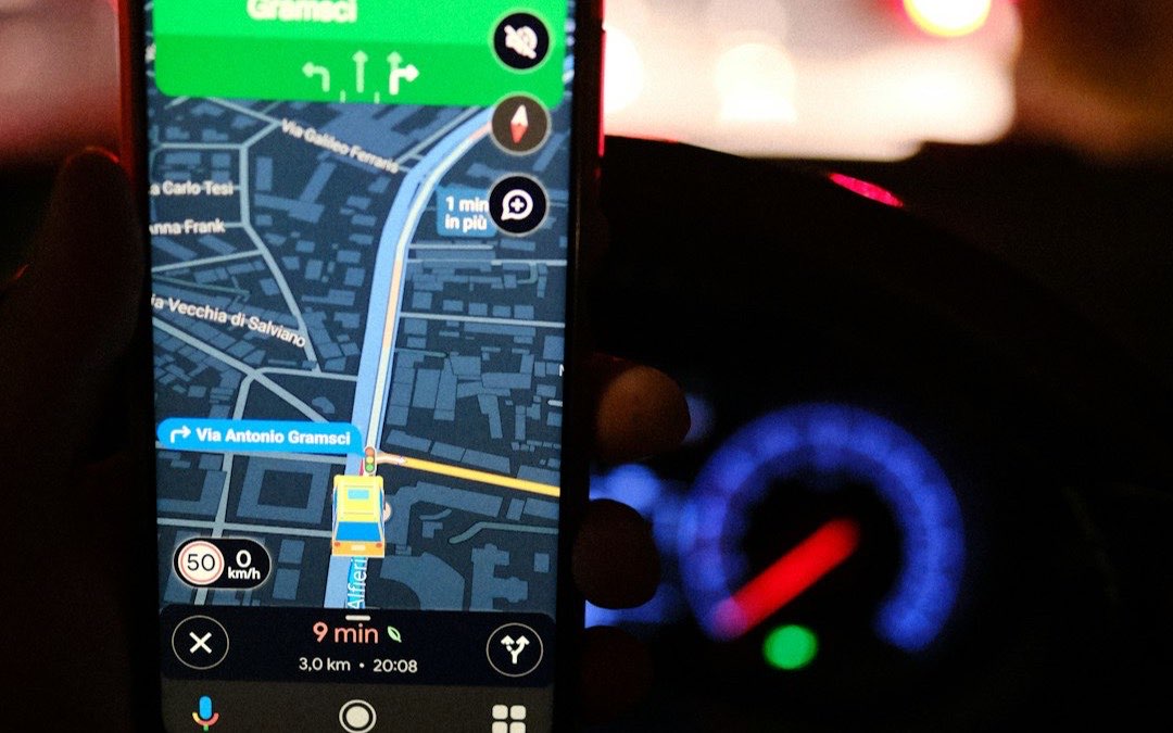 Hand holding a smartphone showing a navigation app on a city street at night